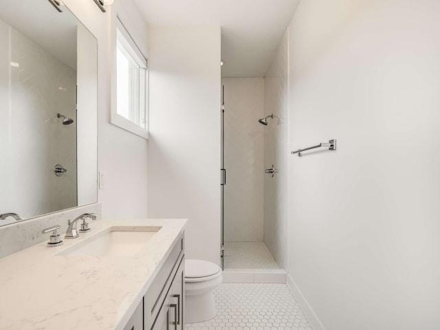 bathroom with vanity, tile patterned flooring, toilet, and tiled shower