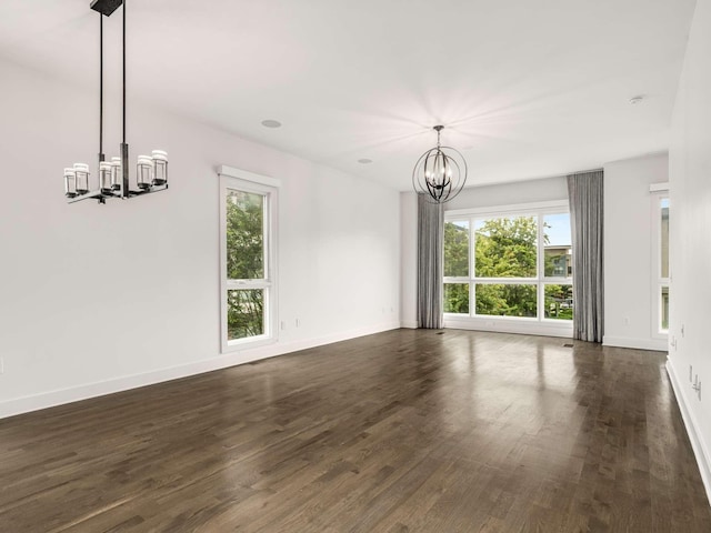 unfurnished dining area featuring a chandelier, healthy amount of natural light, dark wood-style flooring, and baseboards