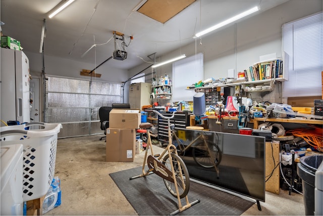 garage featuring a garage door opener, a workshop area, and white refrigerator with ice dispenser