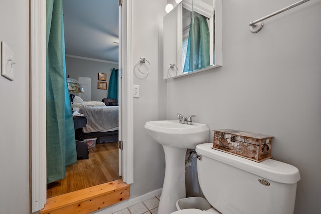 bathroom featuring ornamental molding, hardwood / wood-style flooring, and toilet