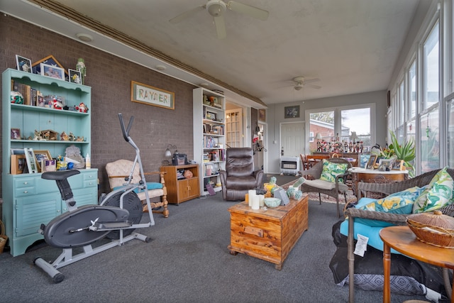 carpeted living room featuring ceiling fan, heating unit, and brick wall