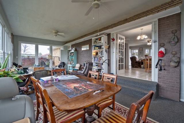 carpeted dining room with ceiling fan and brick wall