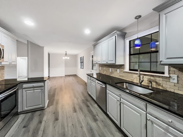 kitchen featuring sink, tasteful backsplash, gray cabinets, pendant lighting, and appliances with stainless steel finishes