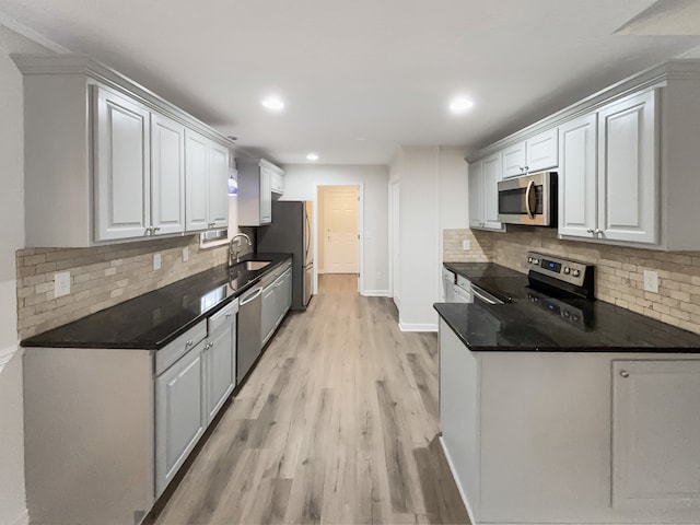 kitchen featuring white cabinetry, sink, appliances with stainless steel finishes, light wood-type flooring, and decorative backsplash