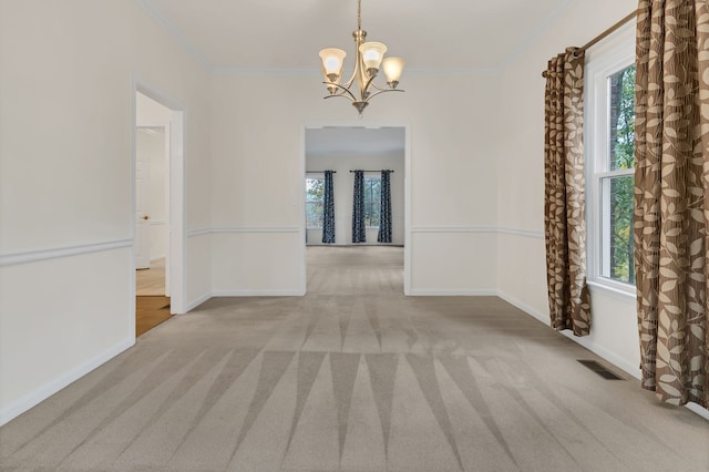 empty room with a wealth of natural light, crown molding, and light colored carpet