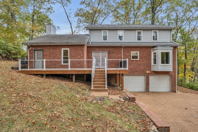 rear view of house featuring a garage and a wooden deck