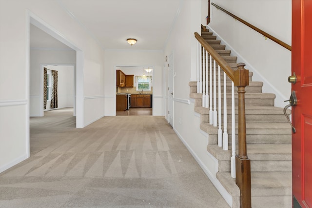 carpeted entrance foyer with crown molding and sink