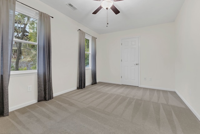 carpeted spare room with a wealth of natural light and ceiling fan