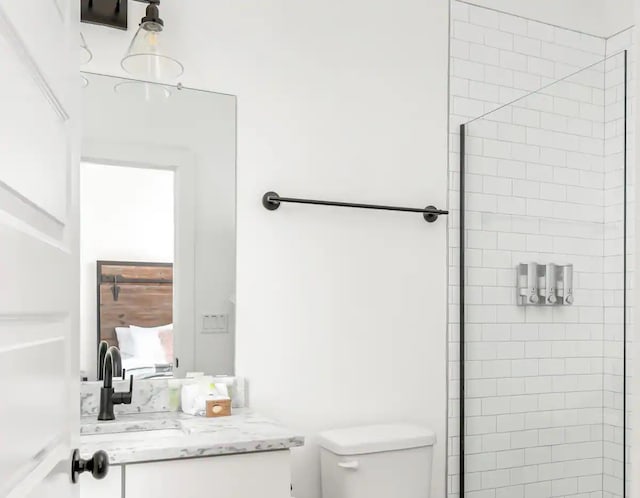 bathroom with tiled shower, vanity, and toilet