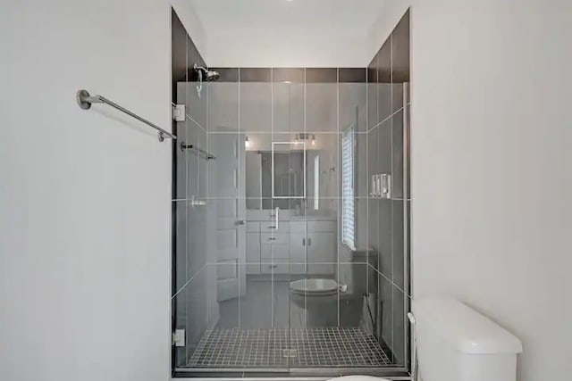 bathroom featuring toilet and a shower with shower door