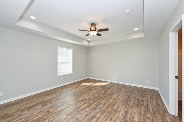 spare room with dark hardwood / wood-style floors, ceiling fan, and a tray ceiling