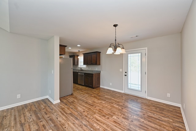 kitchen with stainless steel dishwasher, dark brown cabinets, a notable chandelier, dark wood-type flooring, and white fridge