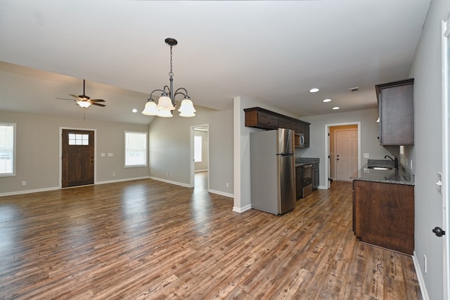 kitchen featuring sink, appliances with stainless steel finishes, dark stone counters, dark brown cabinets, and dark wood-type flooring