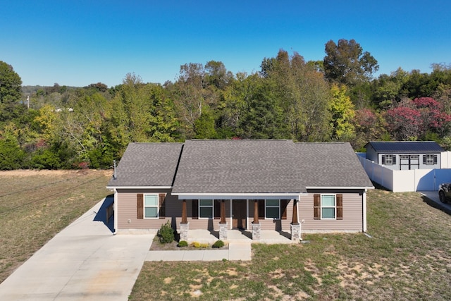 view of front facade with a storage shed, a porch, and a front yard