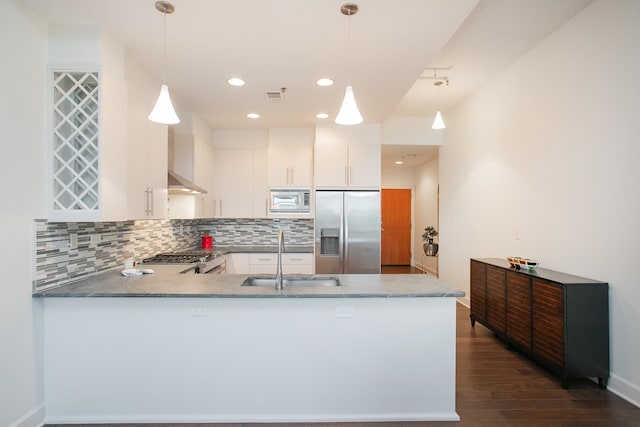 kitchen with sink, kitchen peninsula, appliances with stainless steel finishes, decorative light fixtures, and white cabinets