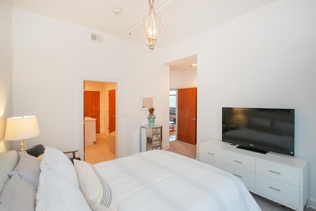 bedroom with ensuite bathroom and light tile patterned floors