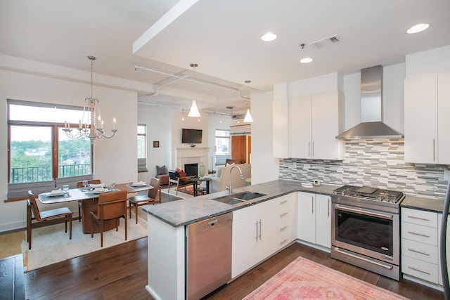 kitchen featuring white cabinetry, sink, appliances with stainless steel finishes, dark wood-type flooring, and wall chimney range hood