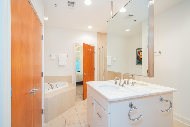 bathroom with vanity, tiled bath, and tile patterned flooring