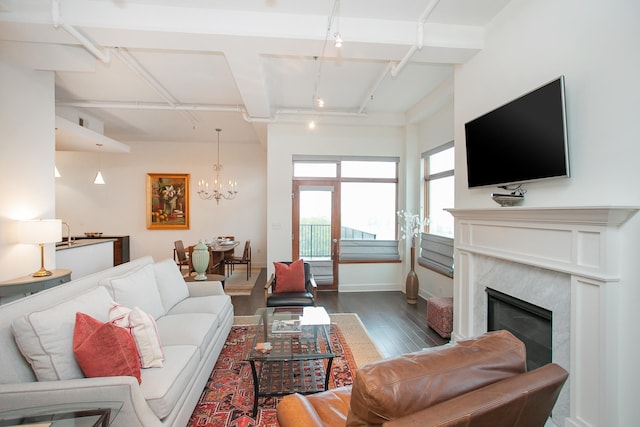 living room with a premium fireplace, dark wood-type flooring, a chandelier, and rail lighting