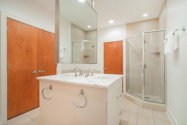 bathroom with a shower with door, vanity, and tile patterned floors