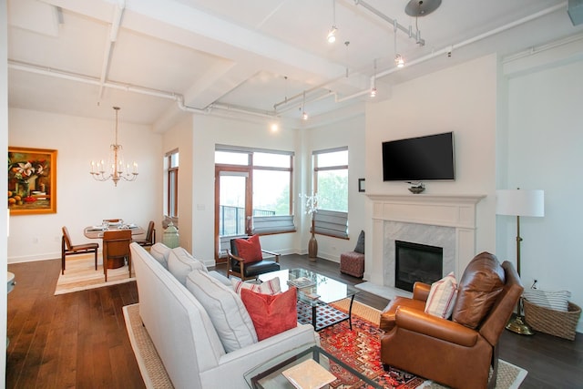 living room featuring dark wood-type flooring, an inviting chandelier, and a high end fireplace