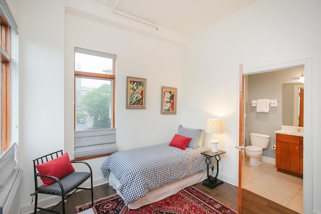 bedroom with track lighting, light hardwood / wood-style floors, and ensuite bath