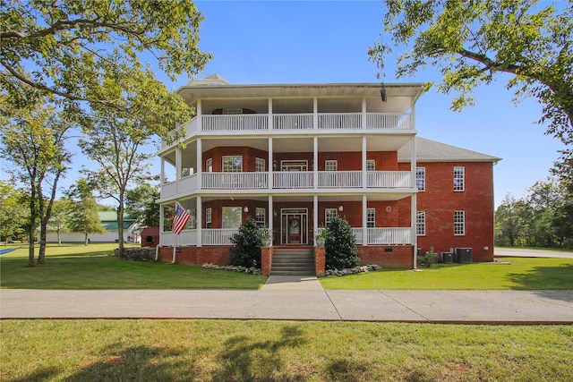 view of front facade with a porch, a front lawn, central AC, and a balcony