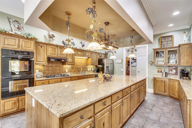 kitchen featuring stainless steel appliances, light stone countertops, decorative light fixtures, backsplash, and a kitchen island