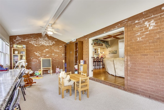 carpeted dining space featuring brick wall, vaulted ceiling with beams, and ceiling fan