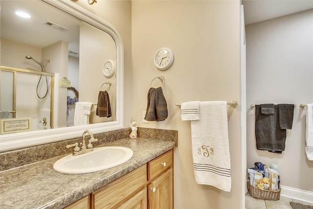 bathroom with an enclosed shower, vanity, and tile patterned floors