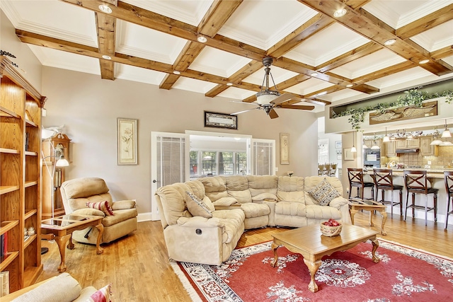 living room featuring ceiling fan, beam ceiling, light wood-type flooring, and coffered ceiling