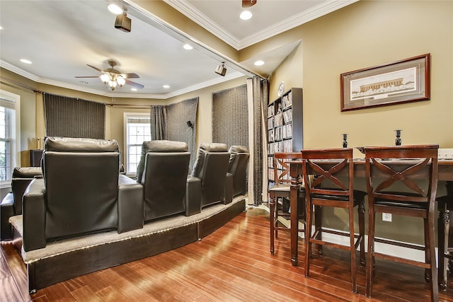 cinema room with ceiling fan, wood-type flooring, and crown molding