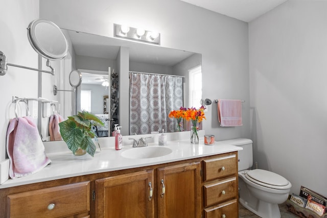 bathroom with toilet, vanity, a wealth of natural light, and ceiling fan