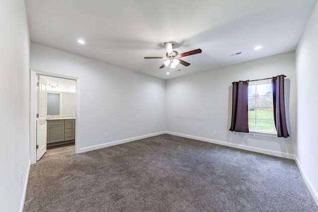 empty room with ceiling fan and dark colored carpet