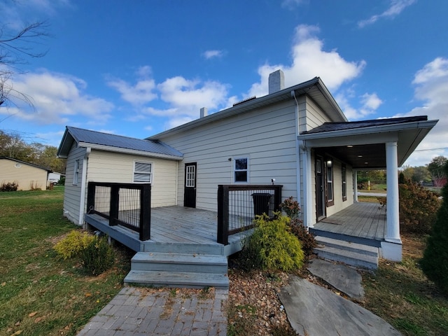 rear view of house featuring a wooden deck and a yard