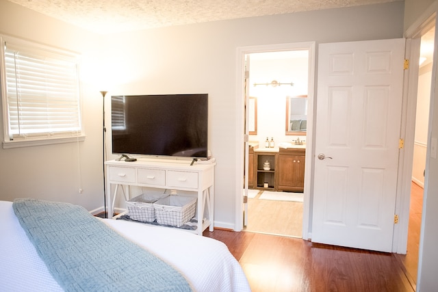 bedroom featuring a textured ceiling, dark hardwood / wood-style floors, ensuite bathroom, and sink