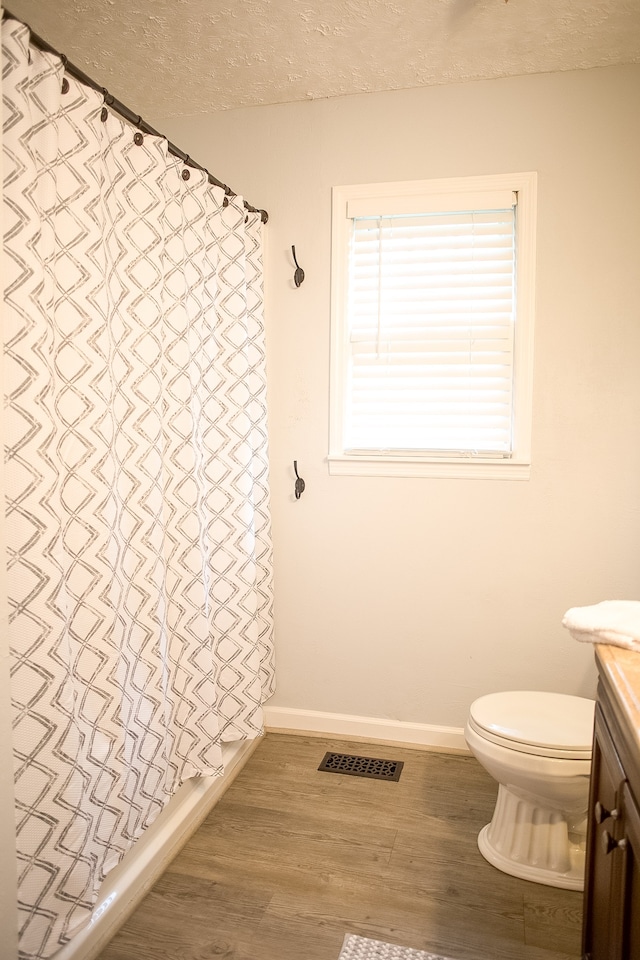 full bathroom featuring shower / bath combo, hardwood / wood-style floors, a textured ceiling, toilet, and vanity