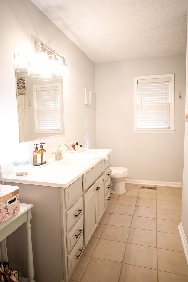 bathroom featuring tile patterned flooring, vanity, toilet, and a textured ceiling