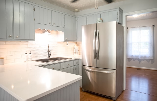 kitchen featuring kitchen peninsula, stainless steel refrigerator, sink, and light hardwood / wood-style floors