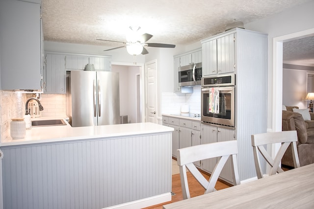 kitchen with kitchen peninsula, stainless steel appliances, tasteful backsplash, and sink