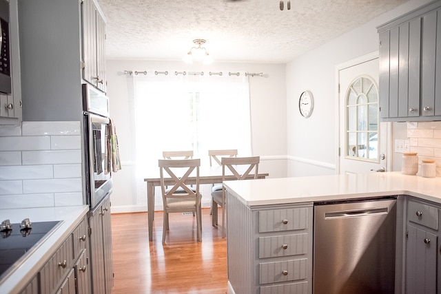 kitchen with gray cabinetry, decorative backsplash, and appliances with stainless steel finishes