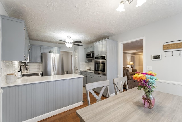 kitchen with sink, gray cabinets, kitchen peninsula, and appliances with stainless steel finishes