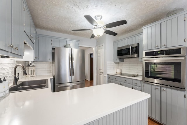 kitchen with gray cabinets, appliances with stainless steel finishes, sink, and kitchen peninsula