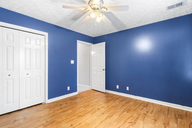 unfurnished bedroom with a textured ceiling, light wood-type flooring, and ceiling fan