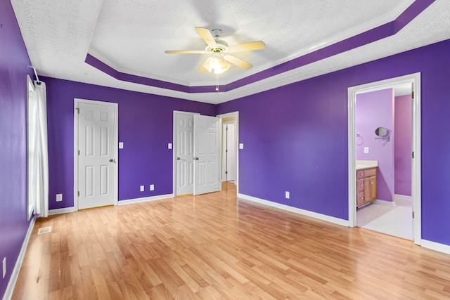 unfurnished bedroom featuring connected bathroom, light wood-type flooring, and a textured ceiling