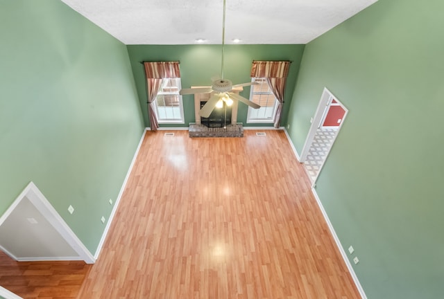 unfurnished living room with hardwood / wood-style floors, ceiling fan, and a textured ceiling