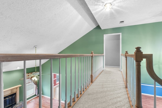 hallway with hardwood / wood-style flooring, a textured ceiling, and vaulted ceiling