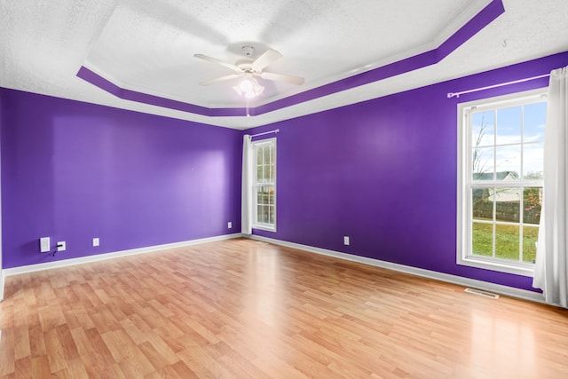 spare room featuring a tray ceiling, ceiling fan, and light hardwood / wood-style flooring