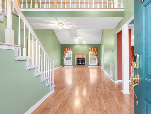 unfurnished living room featuring ceiling fan, a textured ceiling, light hardwood / wood-style flooring, decorative columns, and vaulted ceiling