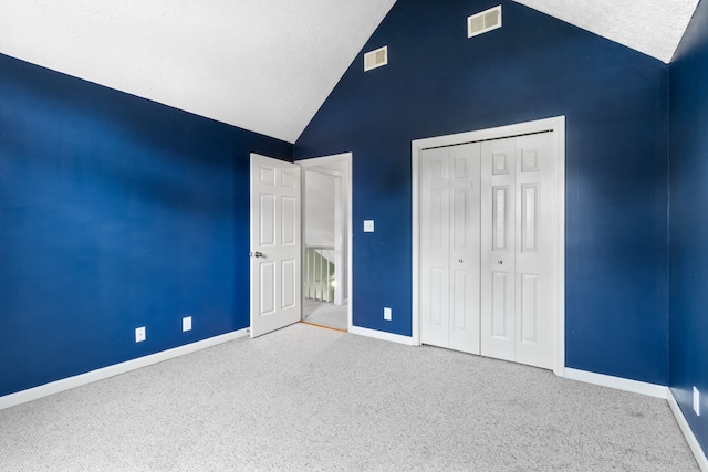 unfurnished bedroom featuring high vaulted ceiling, carpet floors, a textured ceiling, and a closet